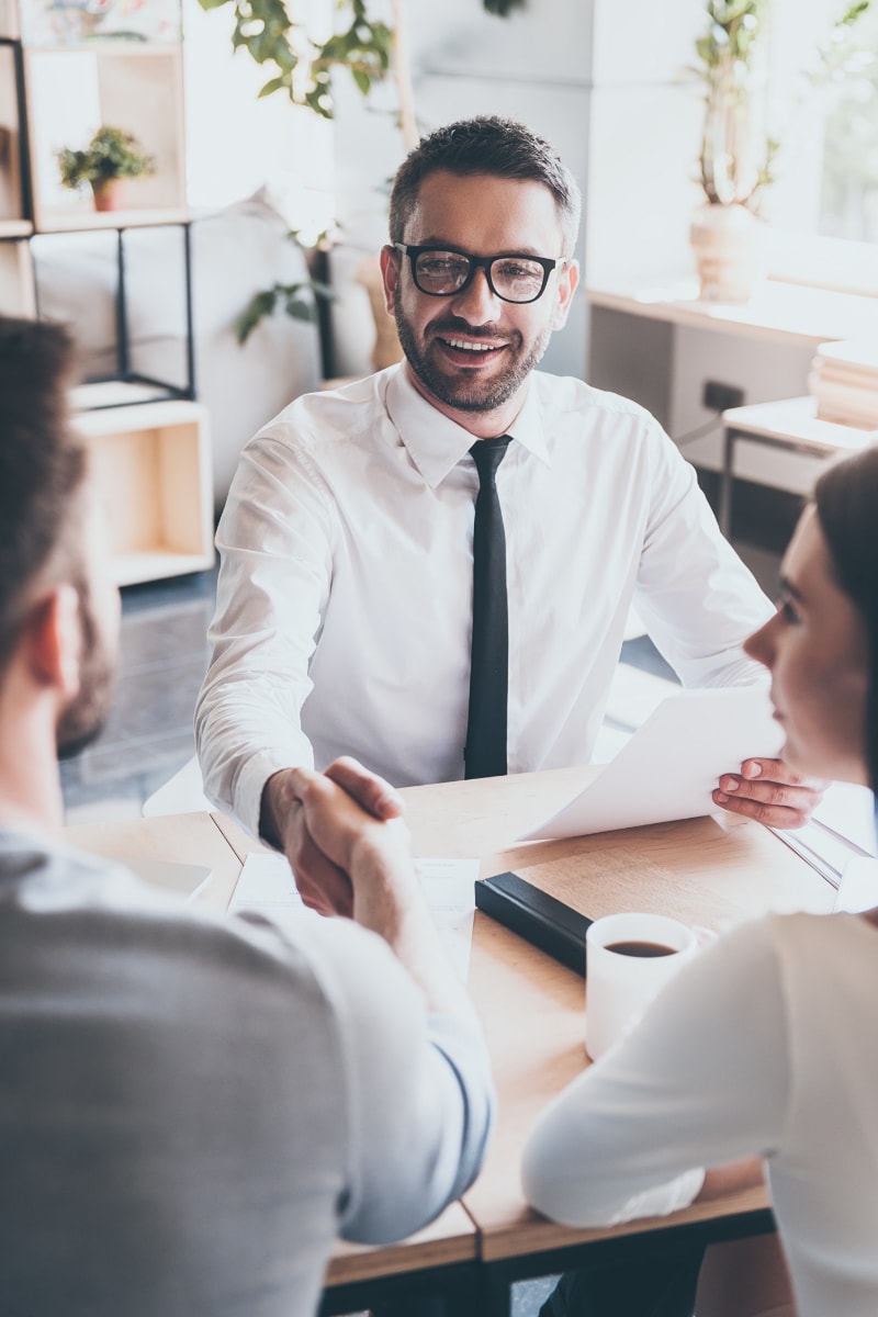 financial advisor with glasses and tie shaking hands with client