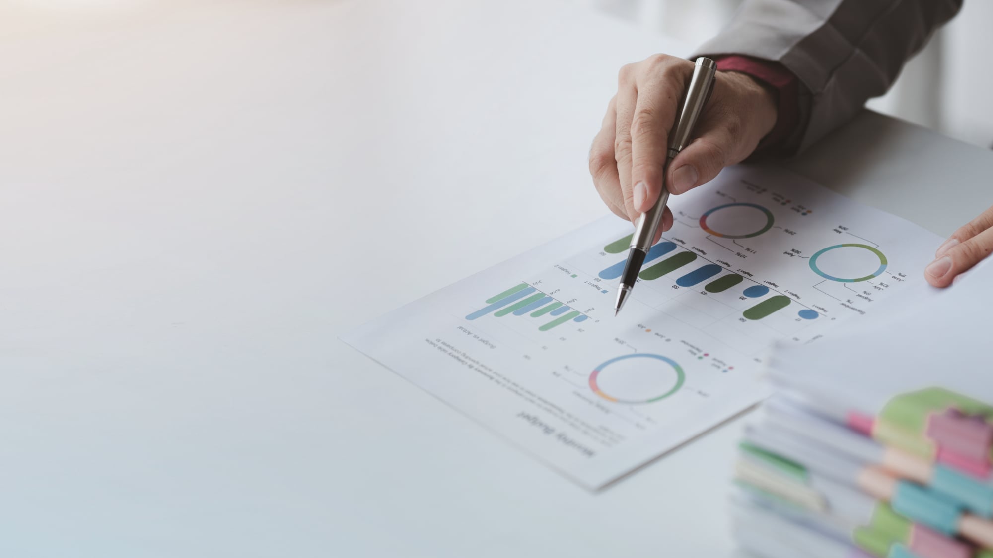person reviewing a document with charts next to a stack of papers